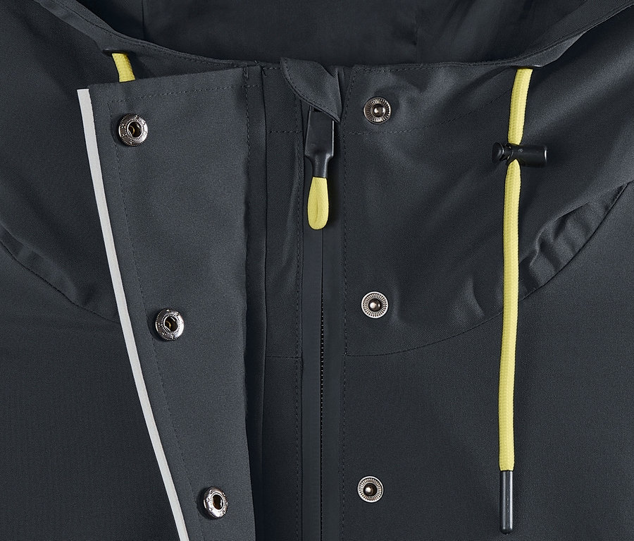 Detail funkčnej parky do dažďa zobrazujúci zapínanie na zips a patentky.