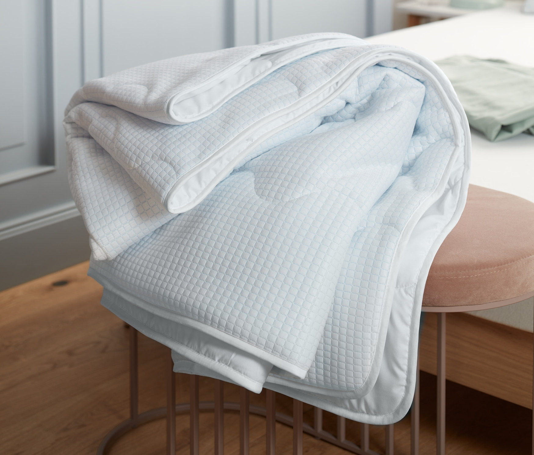 Zložená chladivá prikrývka leží na ružovej stoličke v spálni.