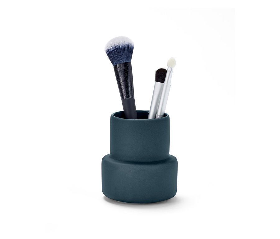 Tri štetce na make-up sú v modrej nádobe na drobnosti.
