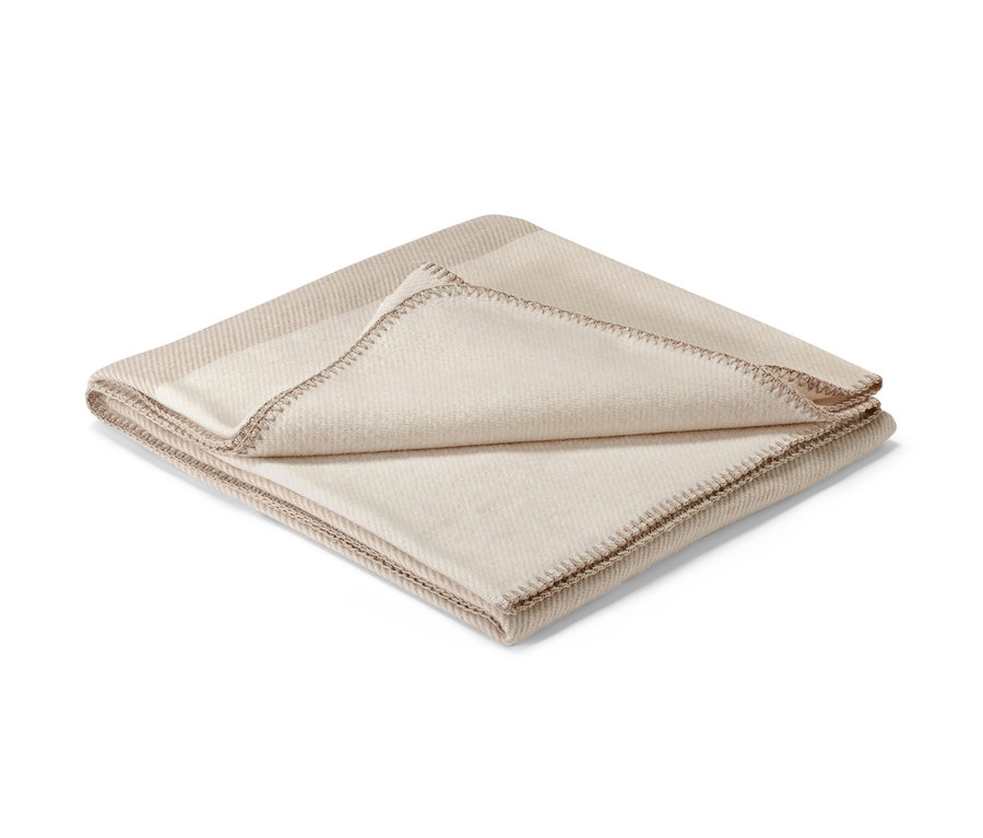 Béžová deka s ozdobným lemom.