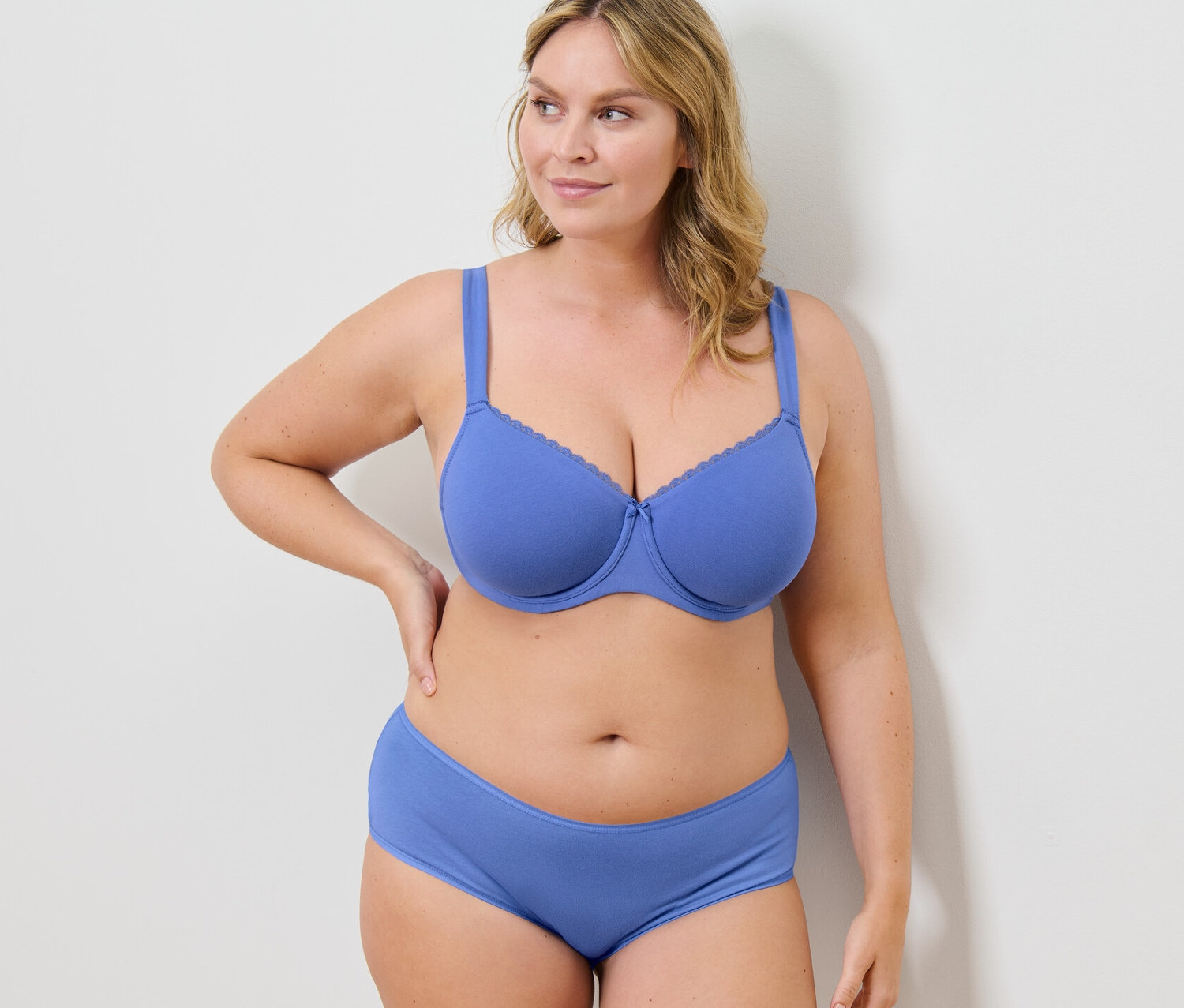 Žena pózuje v modrej podprsenke s kosticami a nohavičkách.