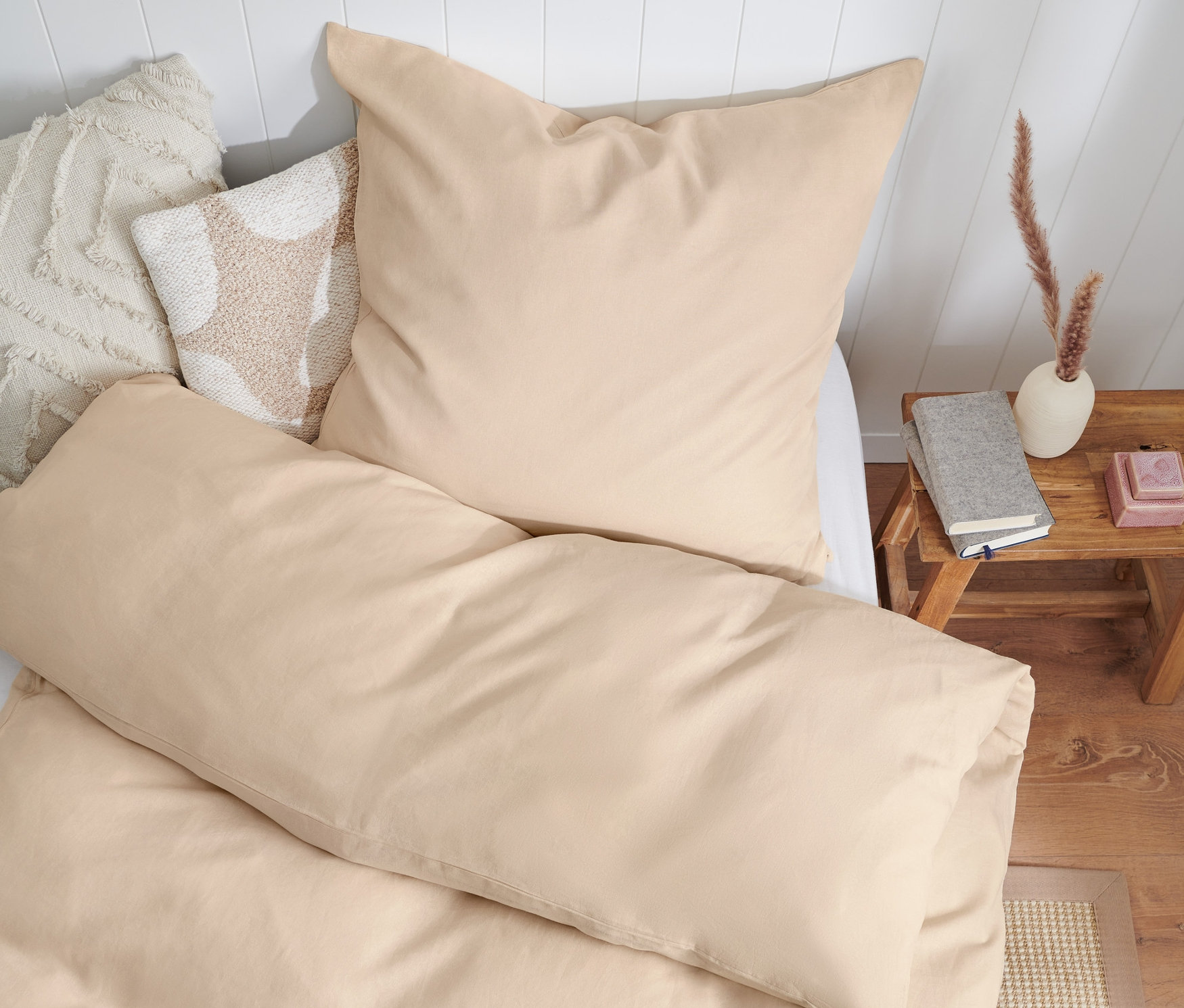 Béžové posteľné obliečky z prané ľanu v štandardnej veľkosti, dvojlôžko a nadmernej veľkosti na posteli s bielym čelom.