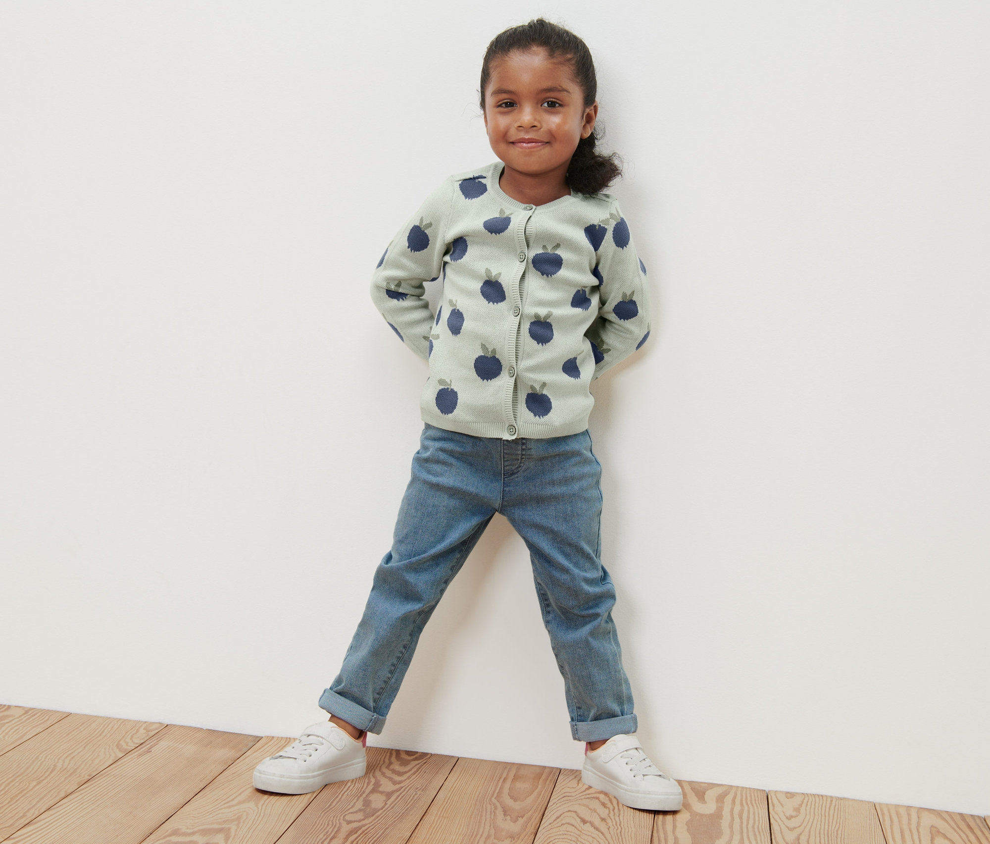 Dievča stojí a má na sebe pletený svetrík s motívom čučoriedky.