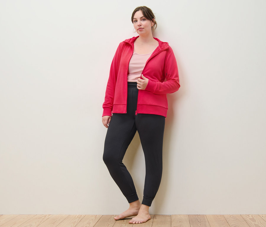 Žena pózuje v ružovej mikine, nohaviciach na jogu a tielkach (2 ks, fuksiové/ružové).