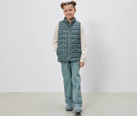 Dievča pózuje v detskej prešívanej veste.