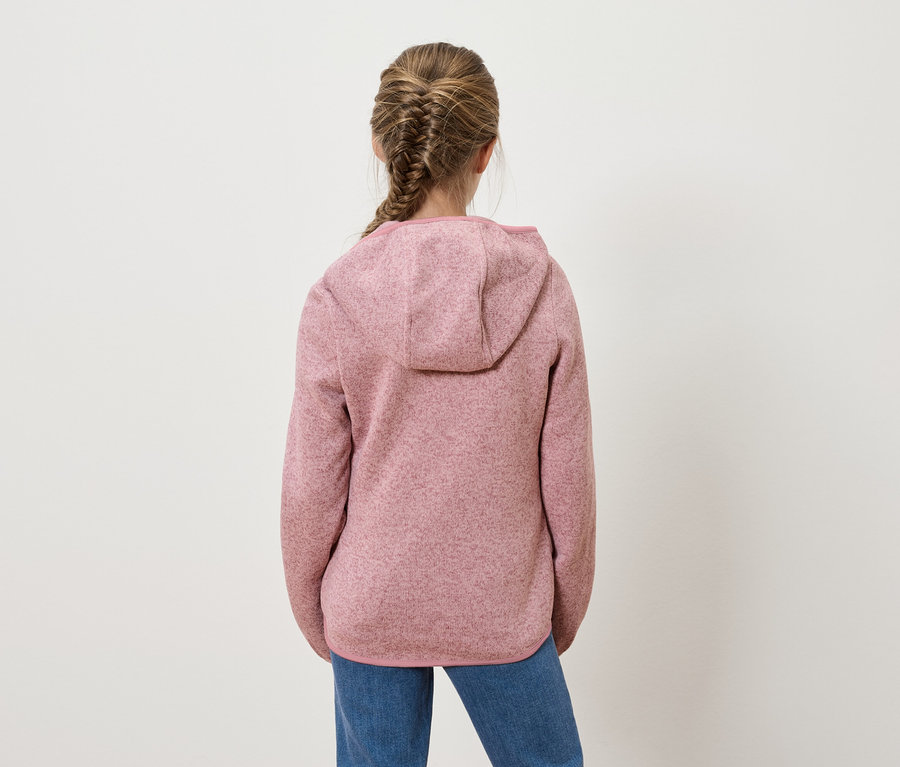 Dievča s vrkočom stojí chrbtom k fotoaparátu a má na sebe ružovú mikinu s kapucňou a džínsy.