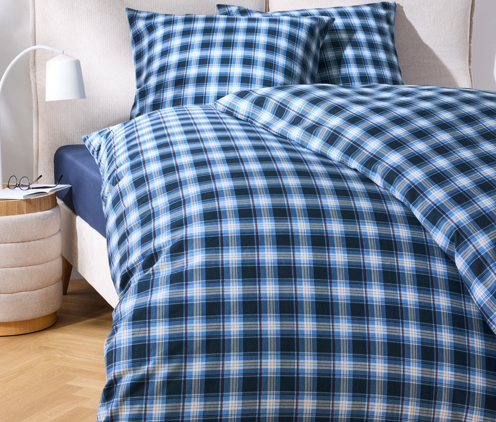 Posteľná bielizeň s modrým kockovaným vzorom na posteli.