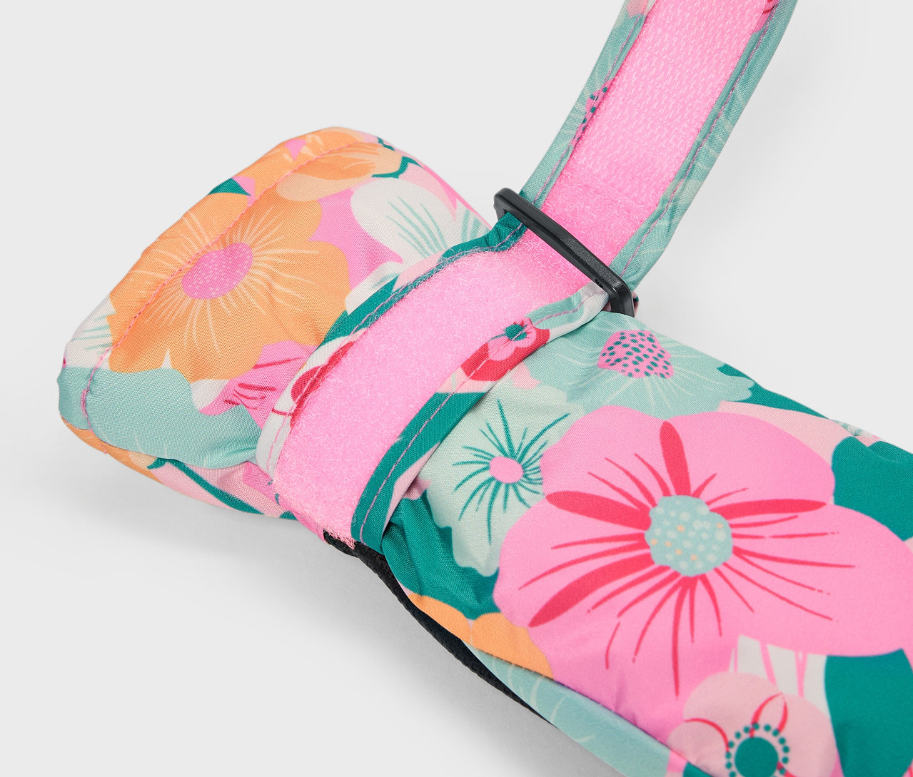 Detail farebnej kvetinovej lyžiarskej rukavice s ružovým remienkom.