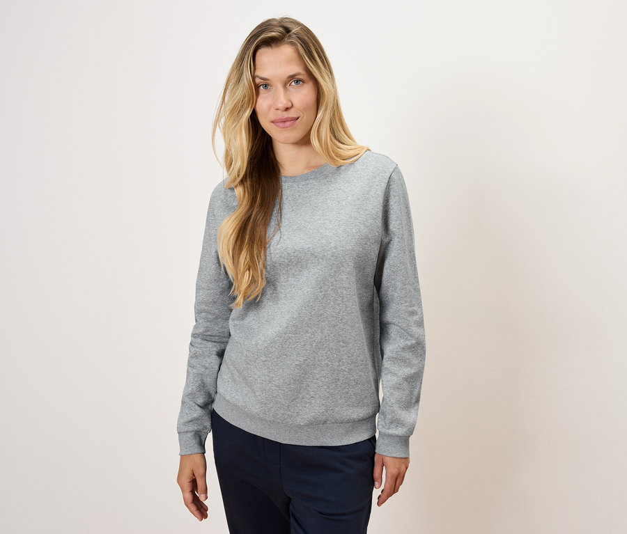 Žena má na sebe sivú mikinu a tmavomodré nohavice.