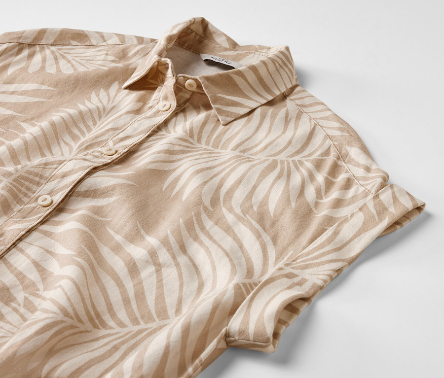 Detail ľanových šiat s potlačou s krátkymi rukávmi a gombíkmi.