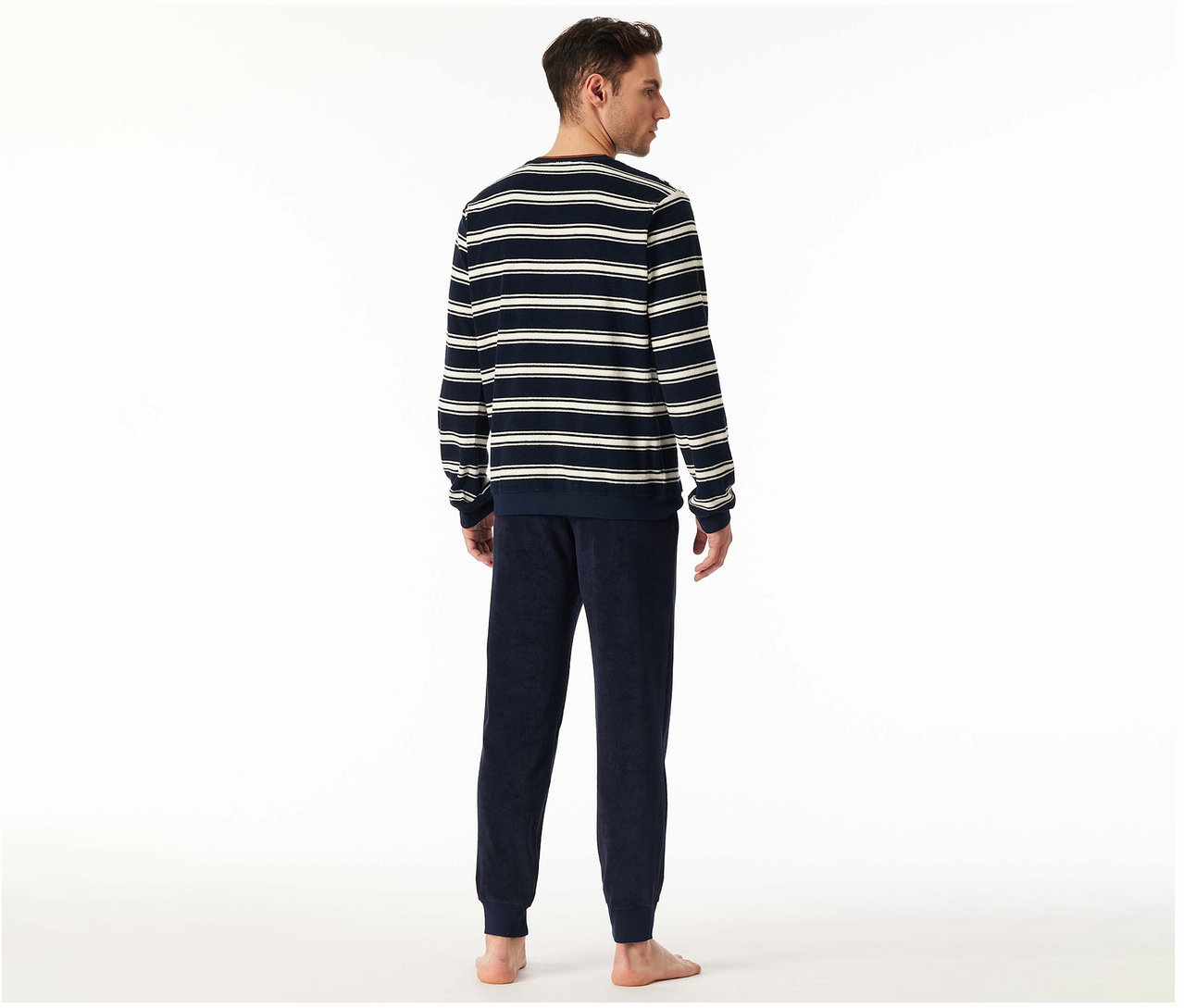 Muž zozadu v pyžamovej súprave z froté SCHIESSER s tmavomodrými nohavicami a pruhovaným topom.
