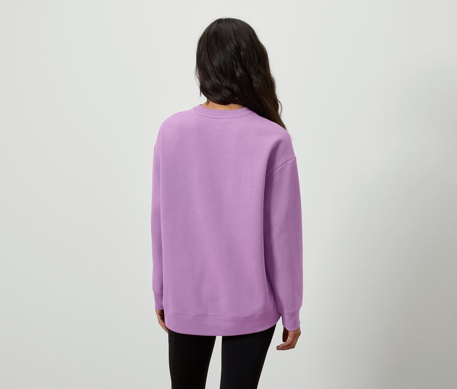 Zozadu je vidieť žena s dlhými tmavými vlasmi v lila mikine a čiernych legínach.