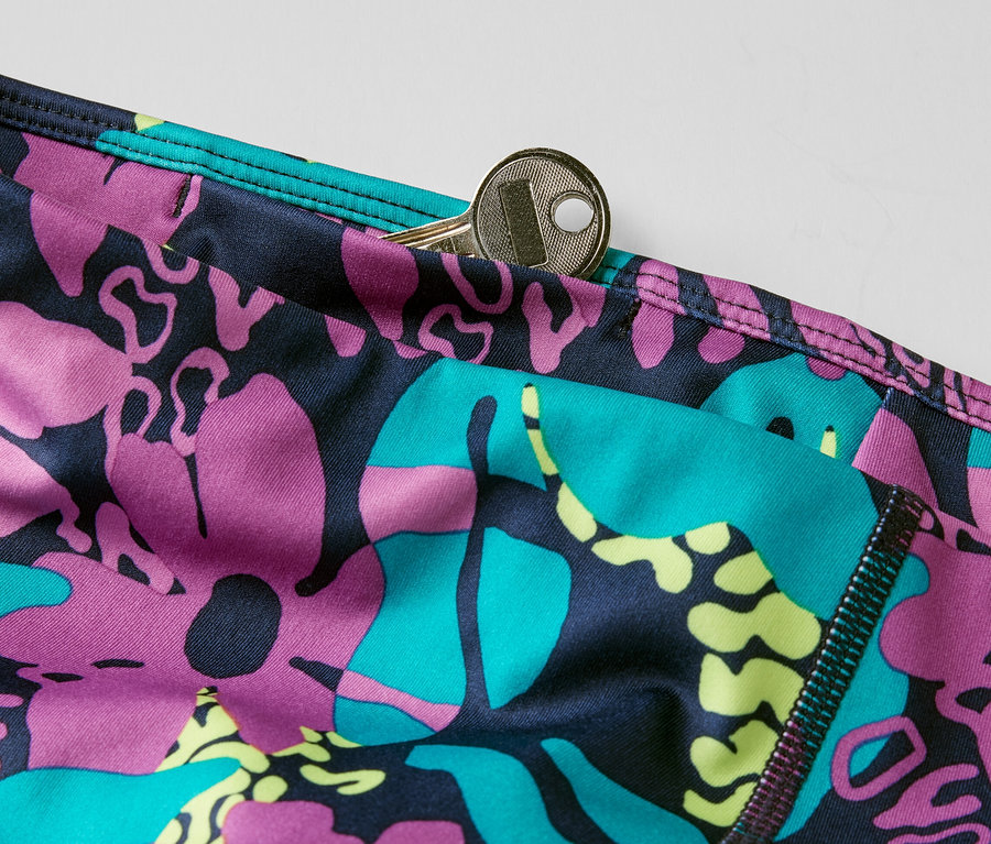 Detail 3/4 športových legín s celoplošnou potlačou a kľúčom vo vrecku.