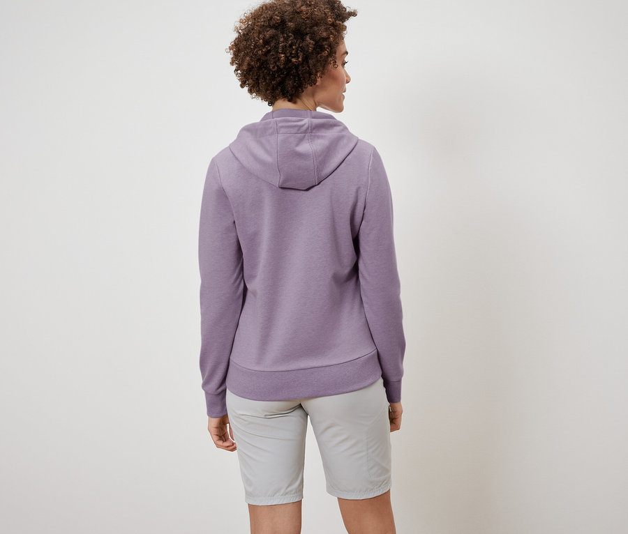 Zozadu je vidieť žena s kučeravými vlasmi v mikine a šortkách.