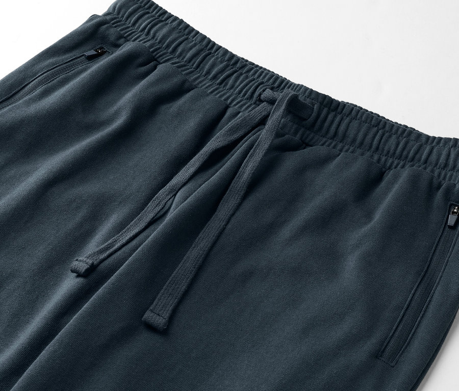 Detailný záber na tmavomodré tepláky so šnúrkou a vreckami na zips.