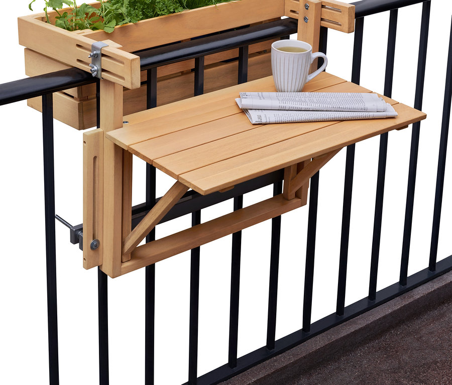 Kvetináč s bylinkami a skladací stolík s novinami a šálkou visia na čiernom balkónovom zábradlí.