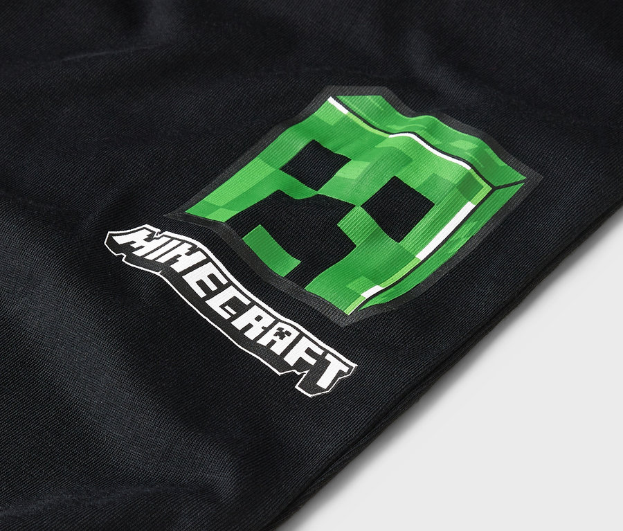 Detailný záber na čierne oblečenie so zeleným motívom Minecraft Creeper.