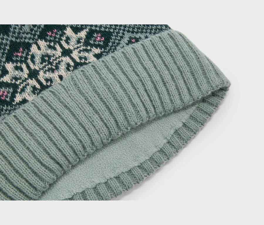 Pletená čiapka s tmavozeleným fair isle vzorom v bielej a ružovej farbe, rebrovaným svetlozeleným lemom a flísovou podšívkou.
