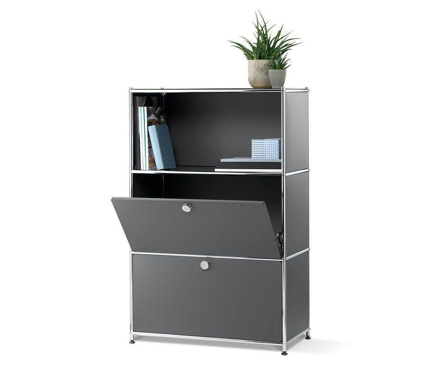 Sivý kovový regál s 2 výklopnými priehradkami, z ktorých jedna je otvorená. Na hornej polici sú knihy a dve rastliny v kvetináčoch.