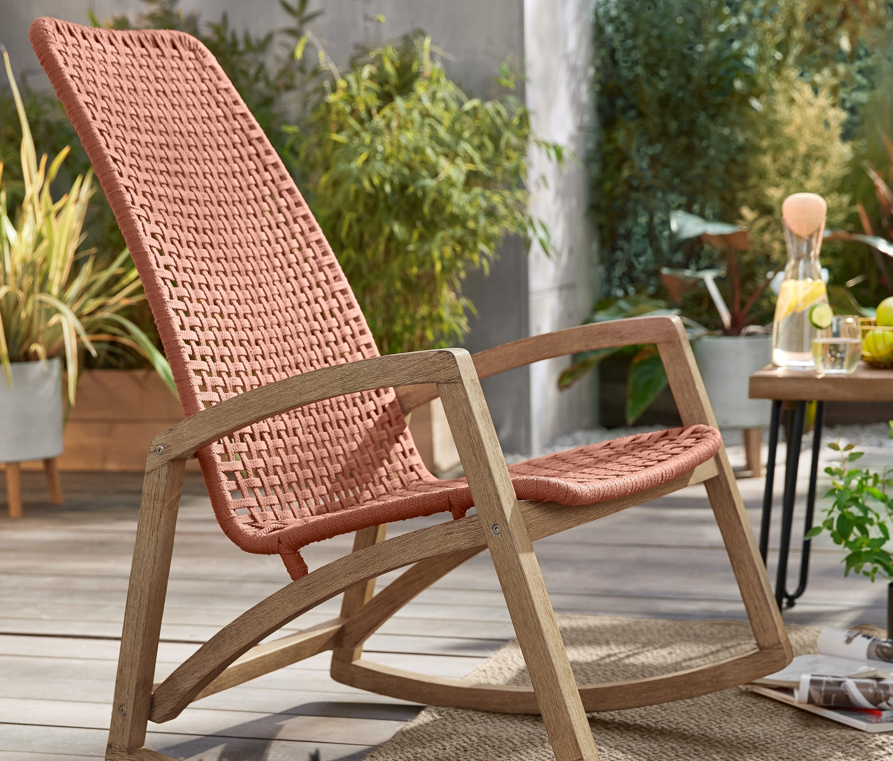 Záhradné hojdacie kreslo »Rope« a svietnik s LED sviečkou na terase. V pozadí kovové konzolové stolíky vo vzhľade betónu, 2 ks a záhradný odkladací stolík.