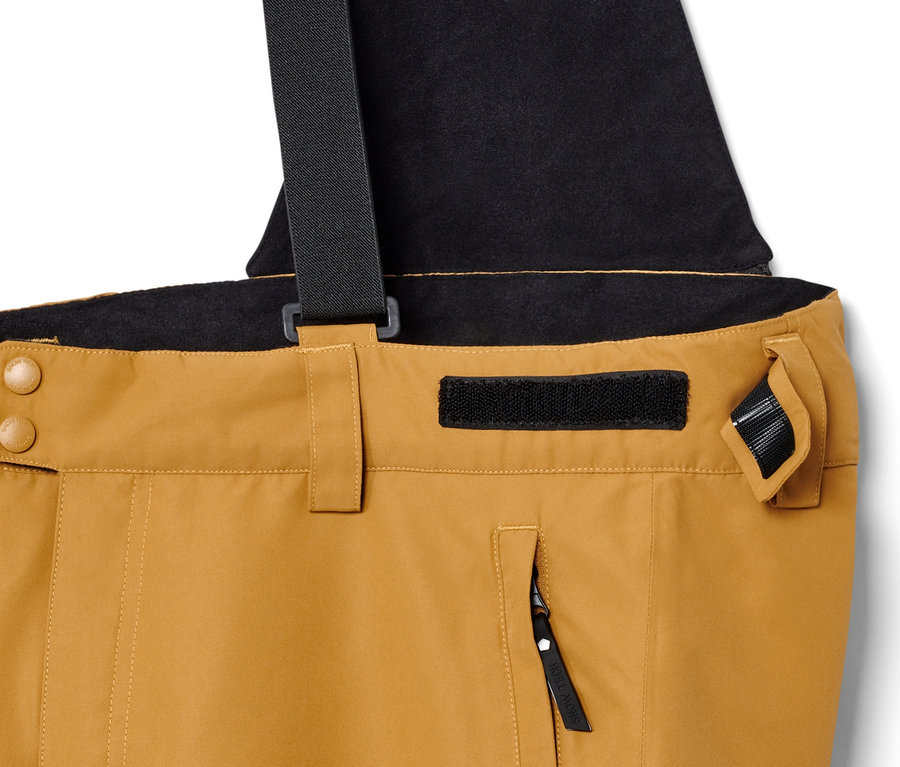 Detail lyžiarskych nohavíc farby ťavej srsti s čiernymi trakami.