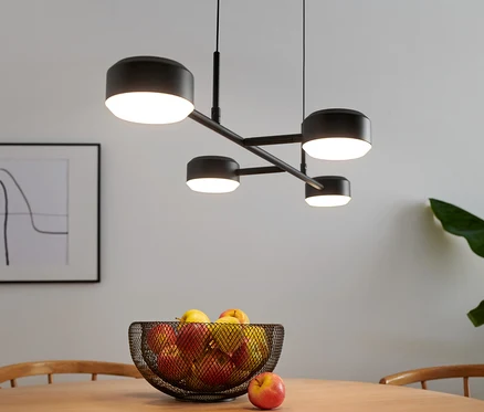 Štvorramenná LED lampa visí nad stolom s ovocím.