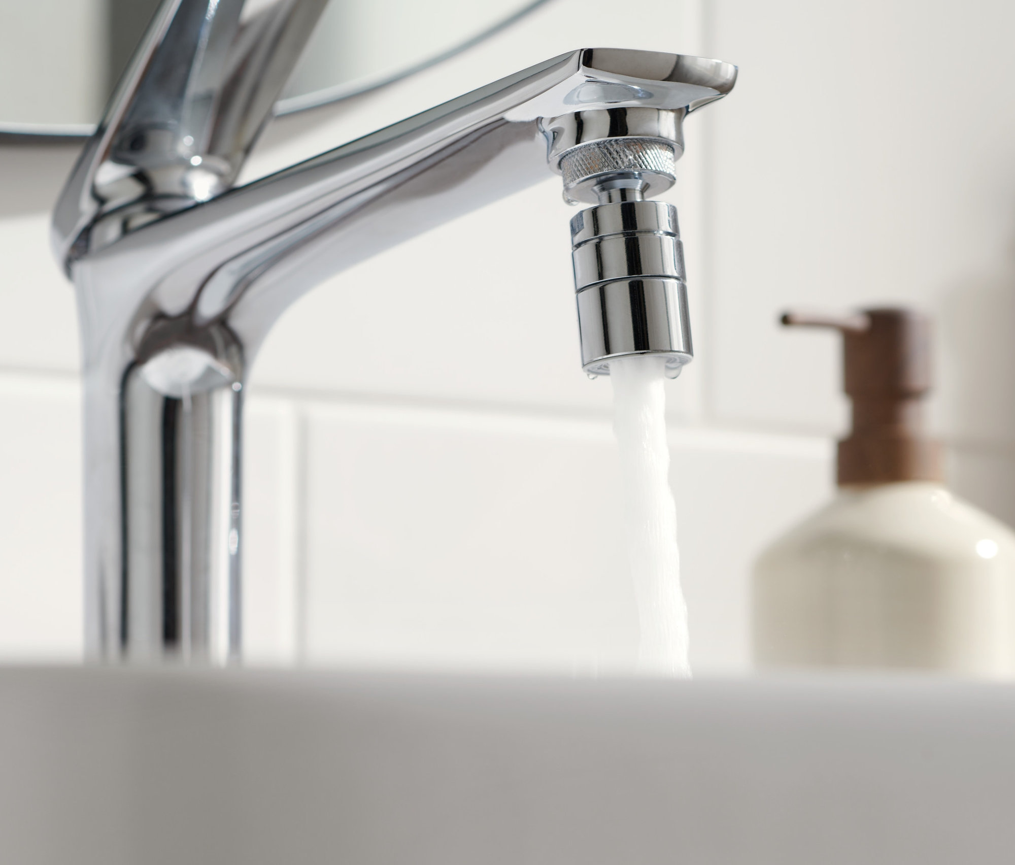 Tečúca voda z vodovodného kohútika s nadstavcom na úsporu vody.