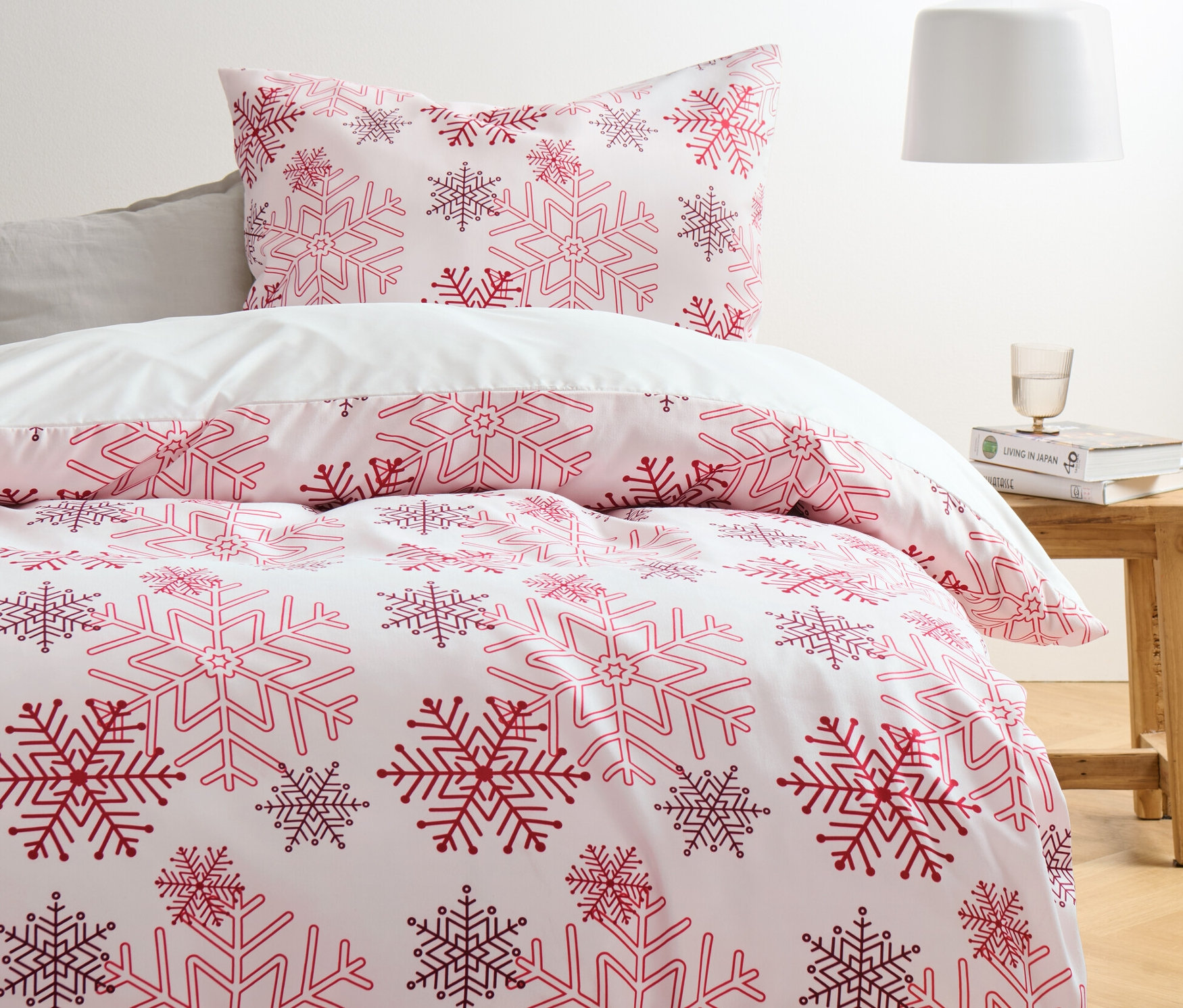 Posteľ s bielymi flanelovými obliečkami z mikrovlákna so vzorom červených a fialových snehových vločiek.