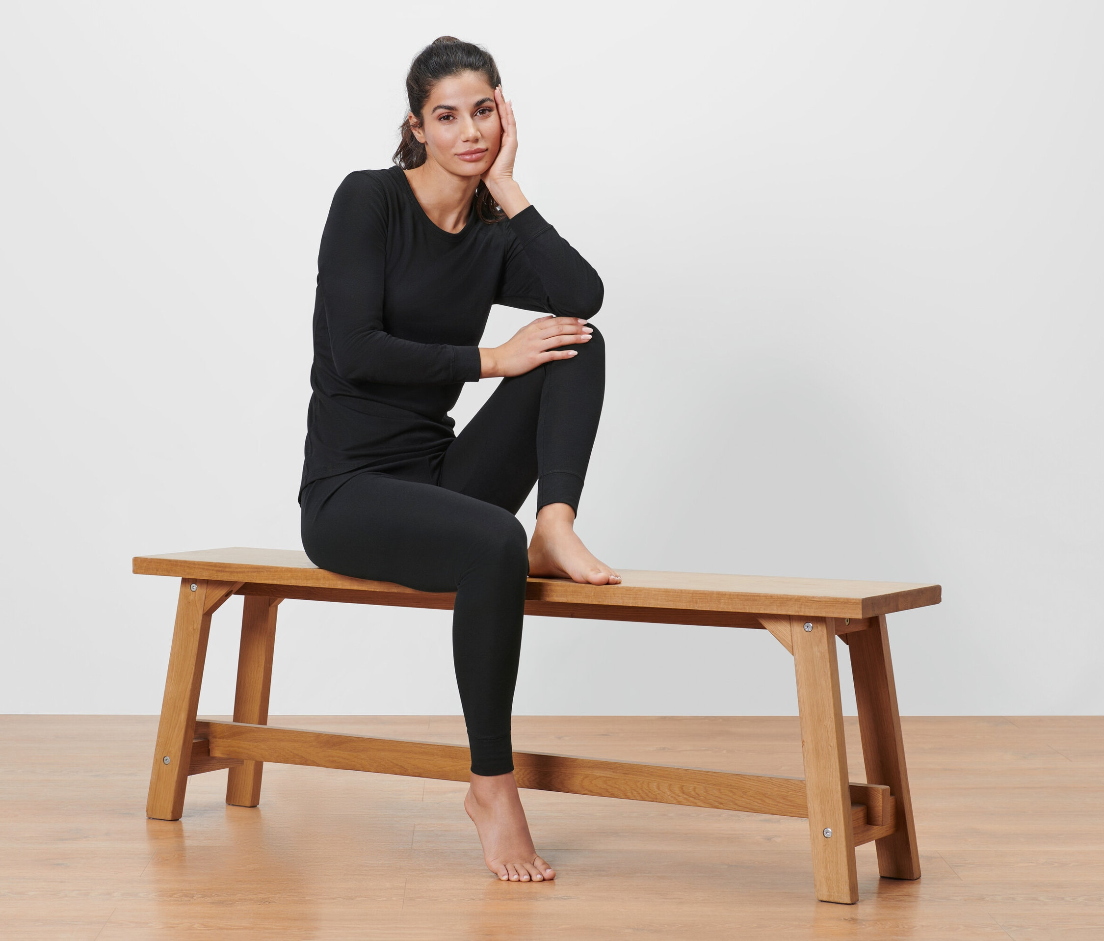 Žena sedí na lavici v čiernej funkčnej termobielizni.