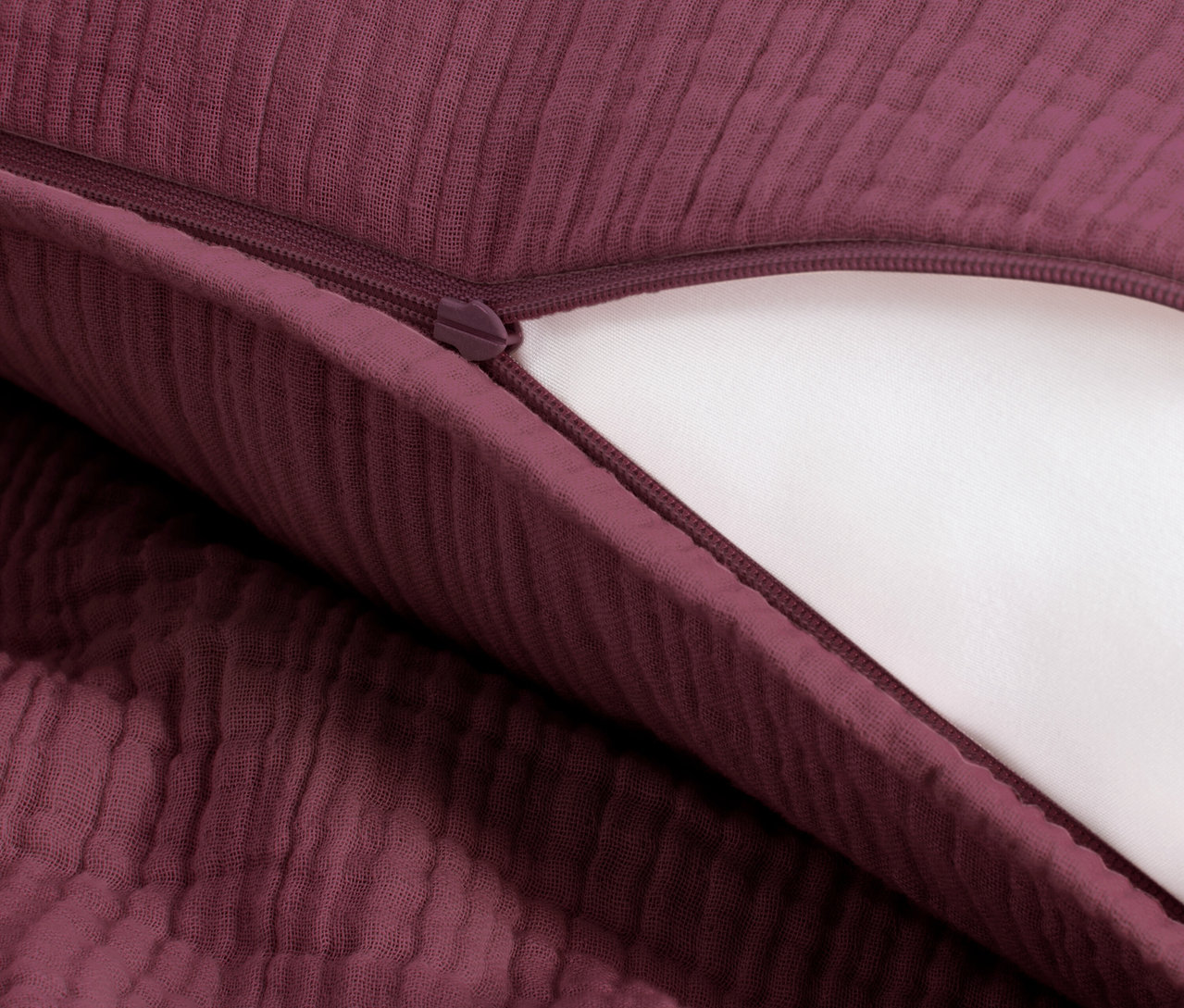 Detailný záber na mušelínovú posteľnú bielizeň vínovej farby štandardnej veľkosti so zipsom.