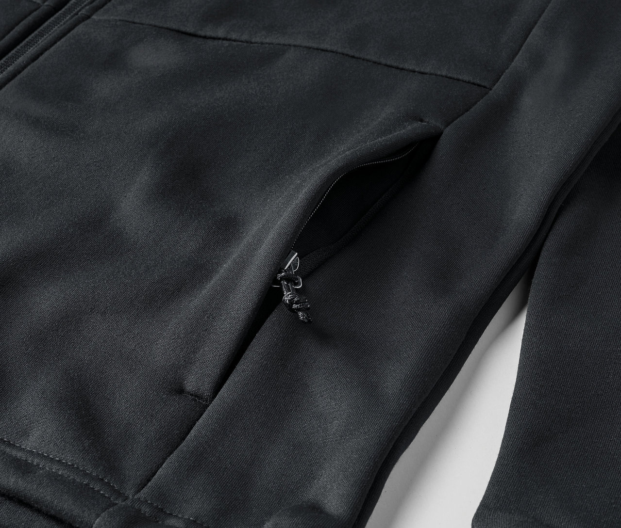 Detail čiernej mikiny so zipsom a vreckom.