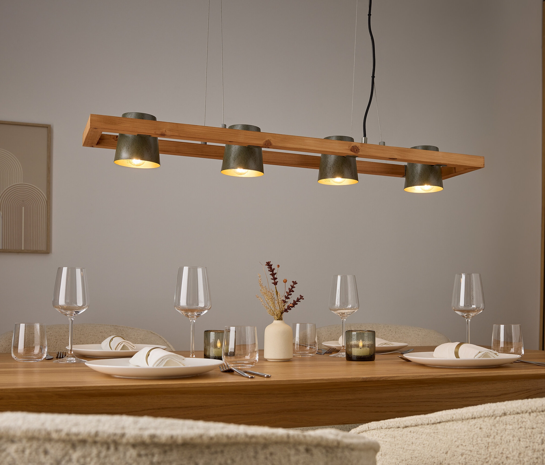 Štyri sivé svetlá nad dreveným stolom s prestieraním a pohármi.