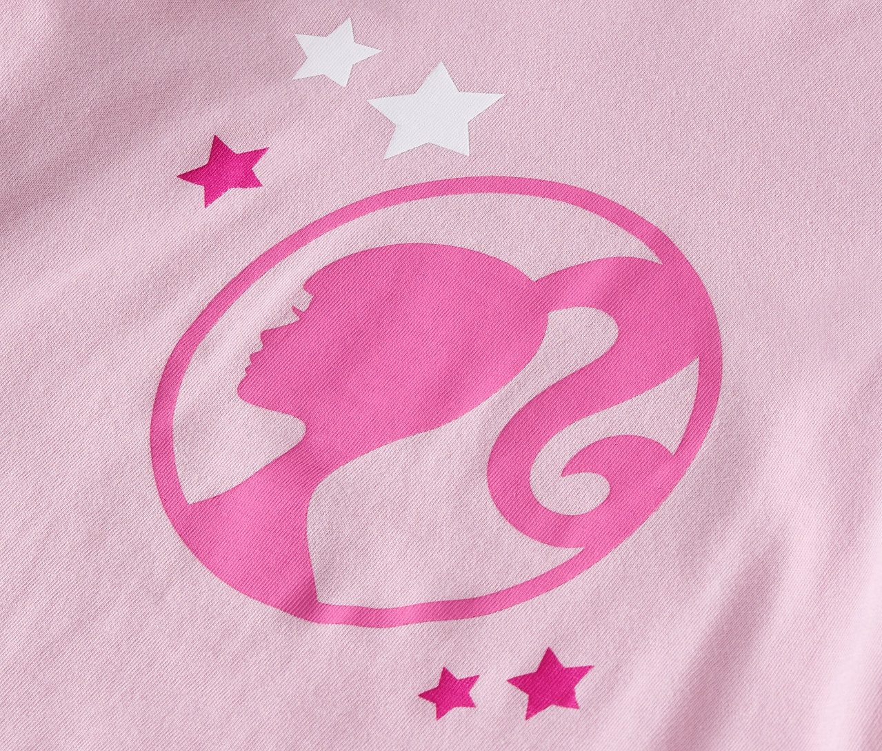 Detail ružového trička s logom Barbie a hviezdami.