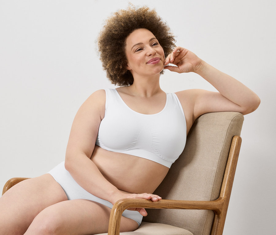 Žena s afro účesom sedí v kresle v bielej podprsenke a nohavičkách.