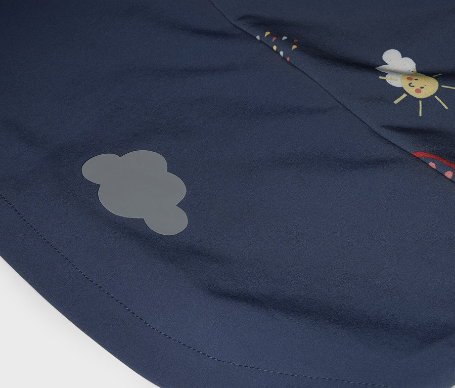 Detailný záber tmavomodrej látky so sivou nášivkou v tvare oblaku a potlačou slnka.