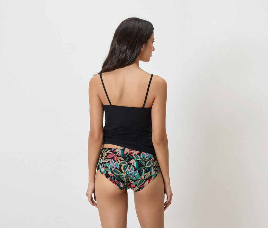 Žena zozadu má na sebe čierny top a nohavičky s kvetinovou potlačou.