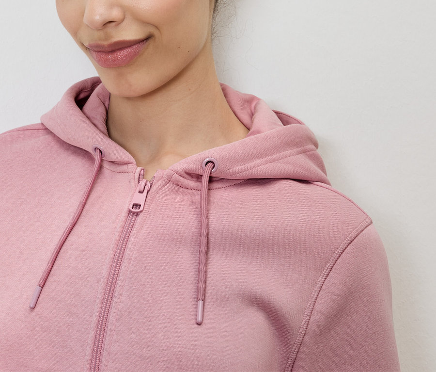 Detailný záber ženy v ružovej mikine s kapucňou na zips.