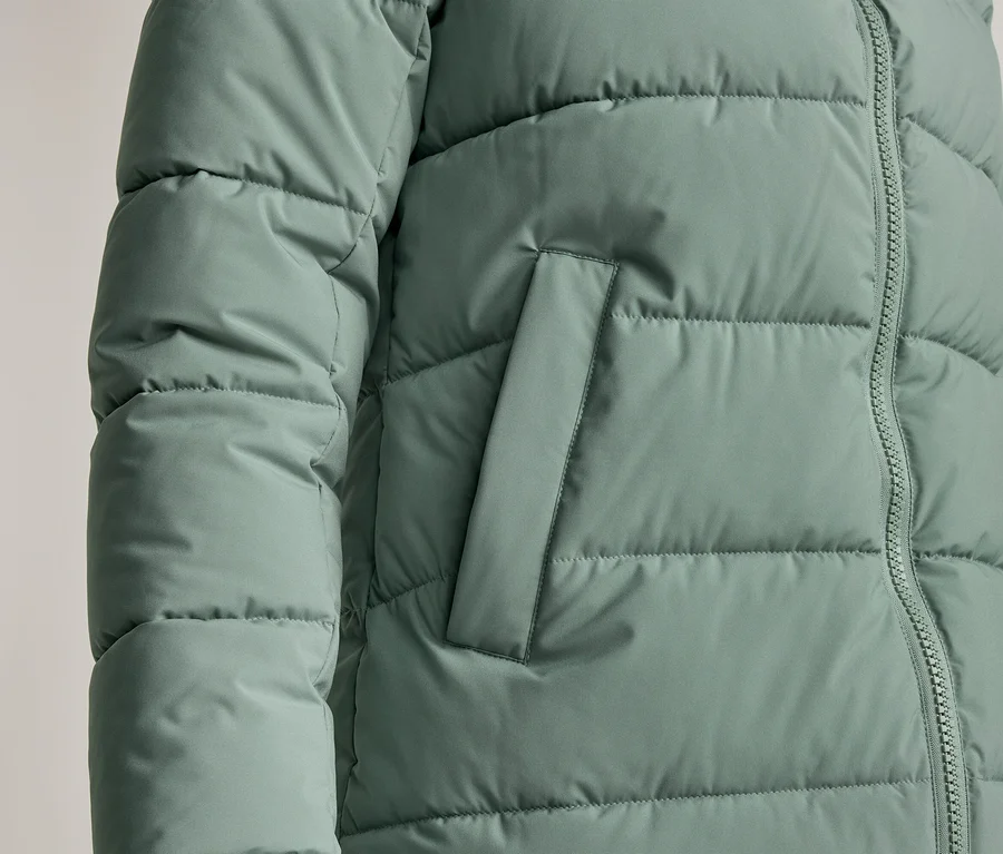 Detailný záber na mätovozelenú prešívanú bundu so zipsom a bočným vreckom.