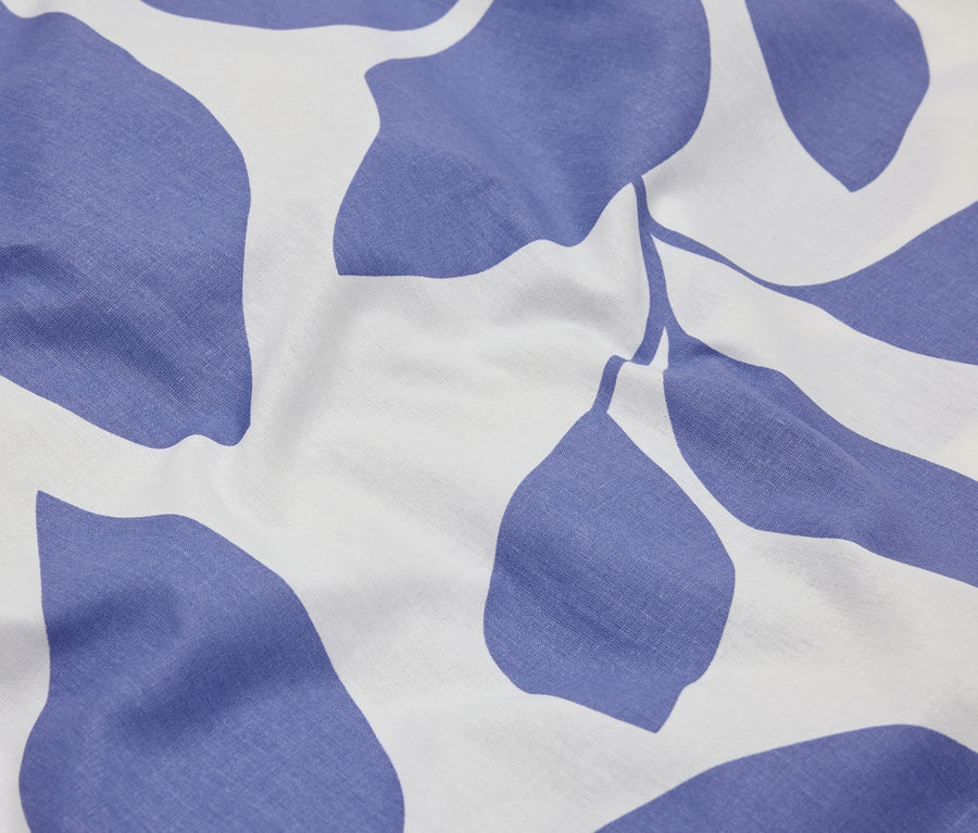 Detail látky s modrým vzorom listov na bielom pozadí.