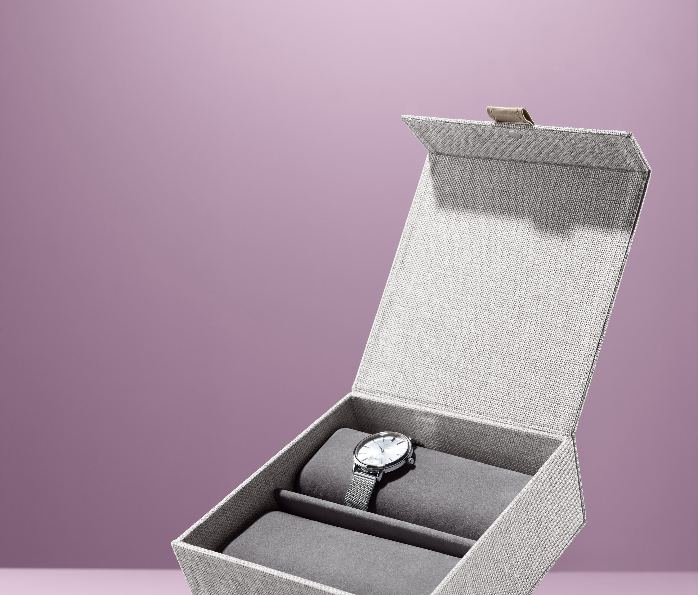 Otvorený úložný box na hodinky so striebornými hodinkami vnútri.