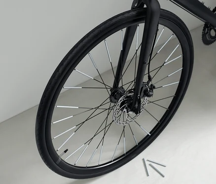 Detailný záber na čierny bicykel s 36 odrazkami na špiciach kolesa.