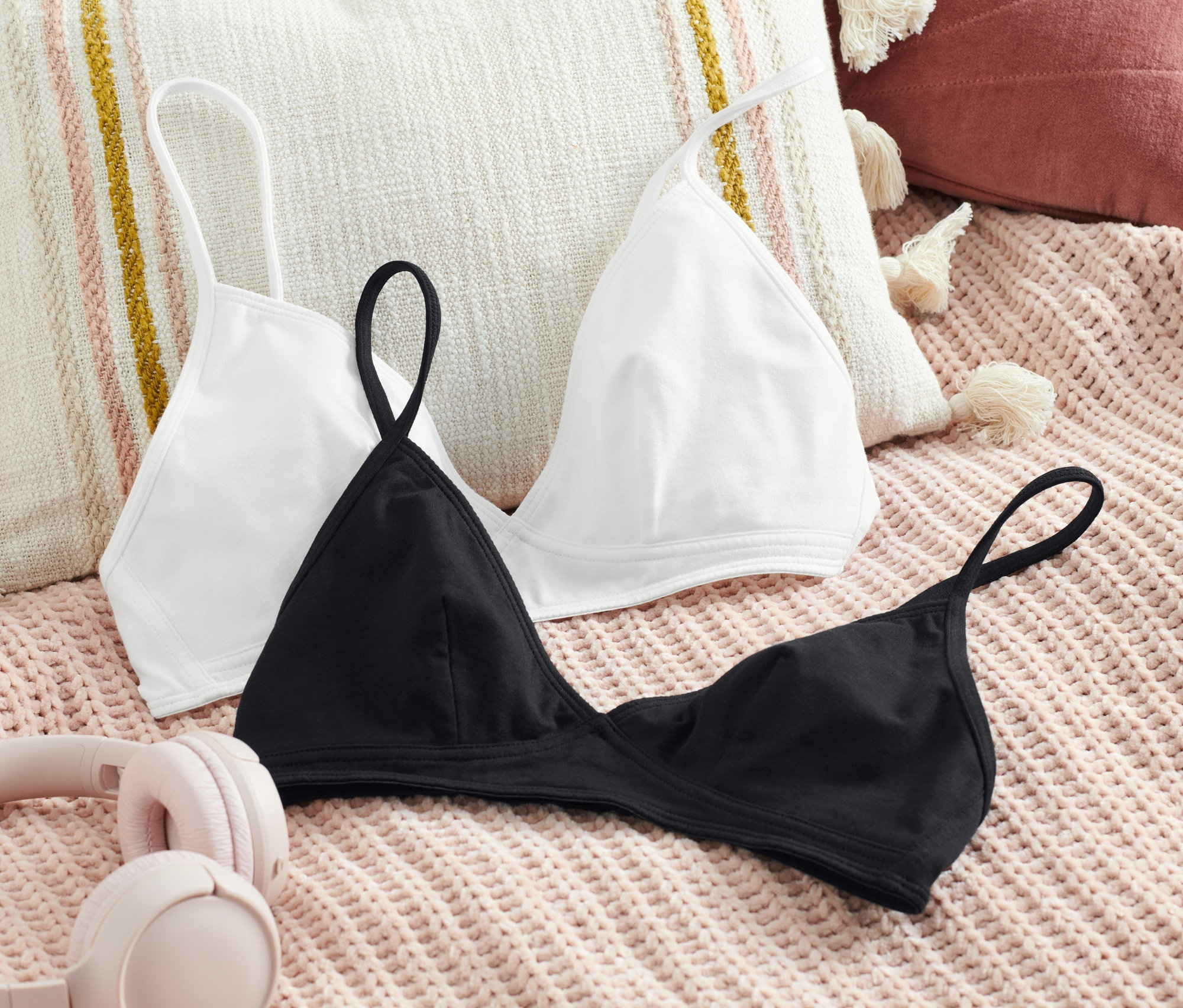 Dievčenské trojuholníkové podprsenky, 2 ks, ležia na deke vedľa slúchadiel.