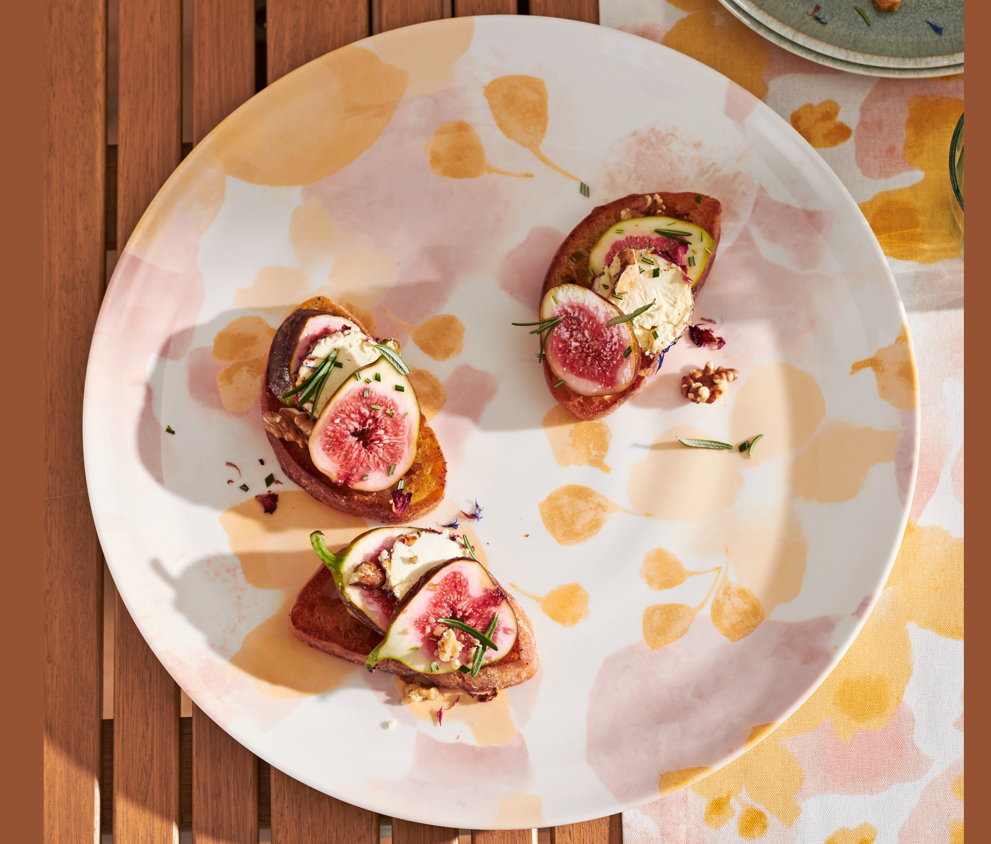 Na drevenom stole leží servírovací tanier s figovými jednohubkami a dve hrušky.