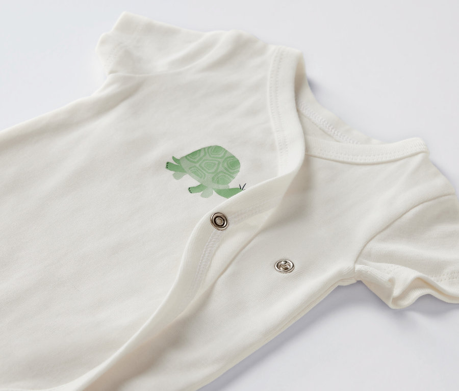 Detail bieleho body s krátkym rukávom a obrázkom korytnačky.