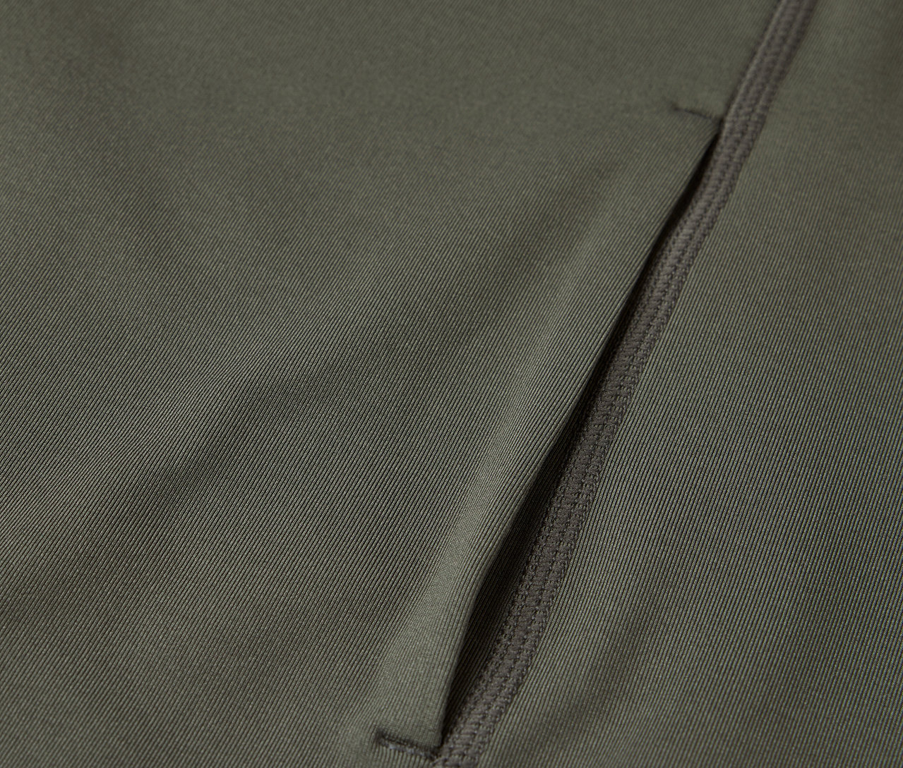 Detailný záber na olivovozelenú látku s vreckom na zips.