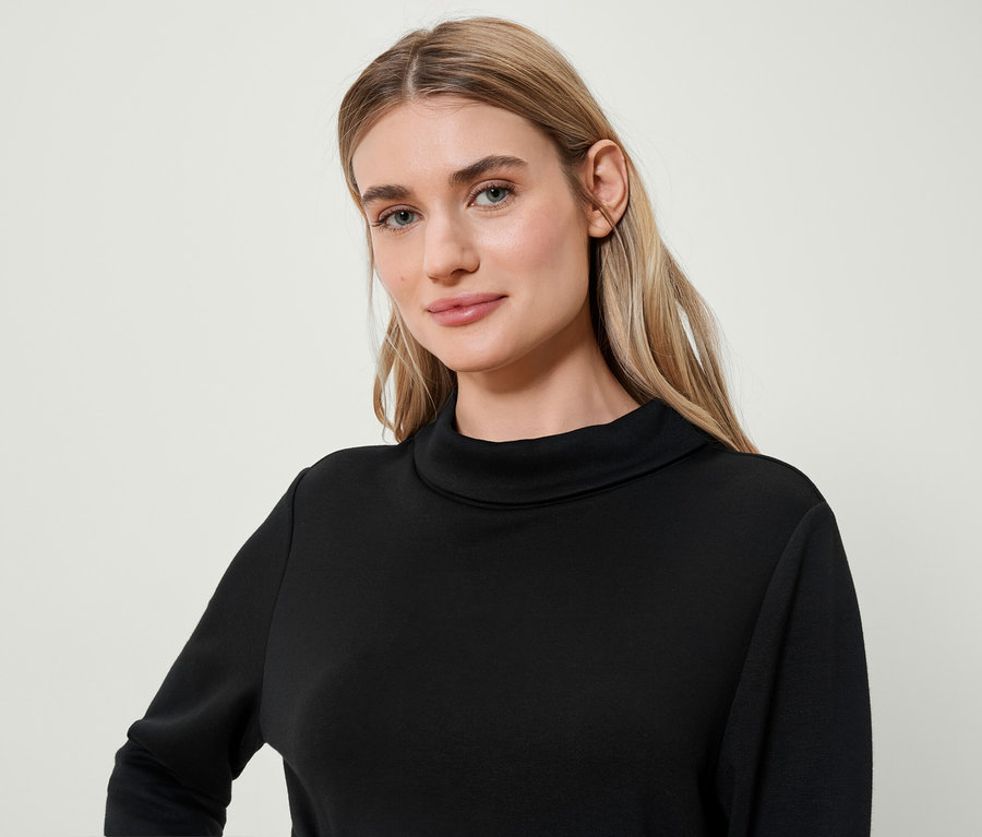 Portrét blondínky v čiernom roláku.