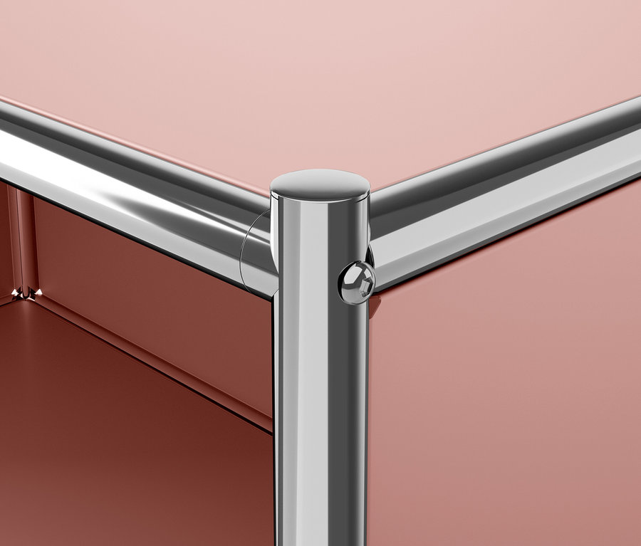 Detail rohu modulárneho nábytku s kovovou nohou a červenohnedou doskou.