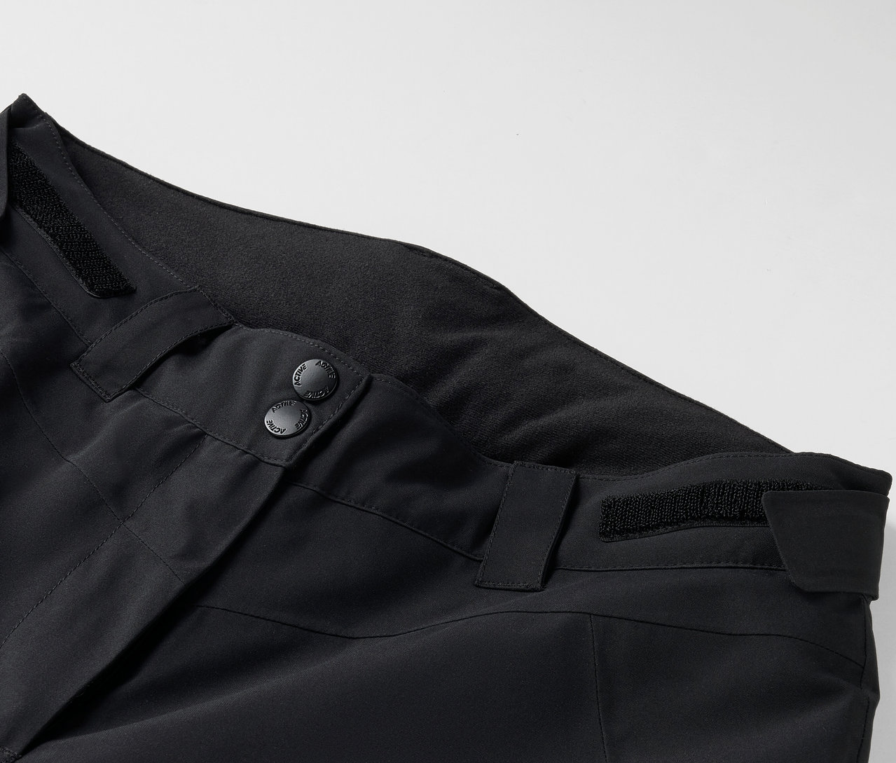 Detail čiernych nohavíc s gombíkmi a pútkami na opasok.