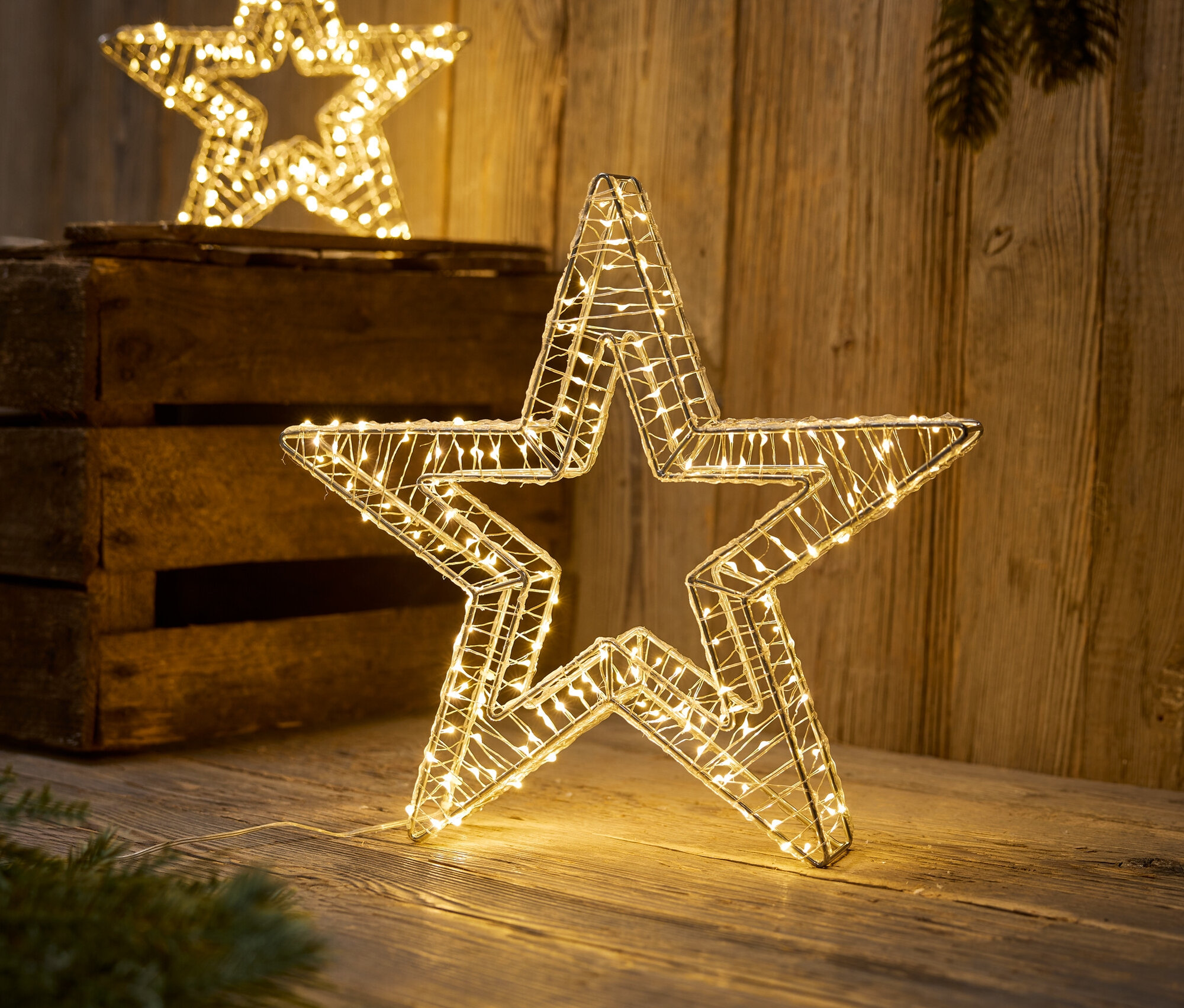 Dve dekoratívne hviezdy s LED svetlami stoja na drevenom povrchu.