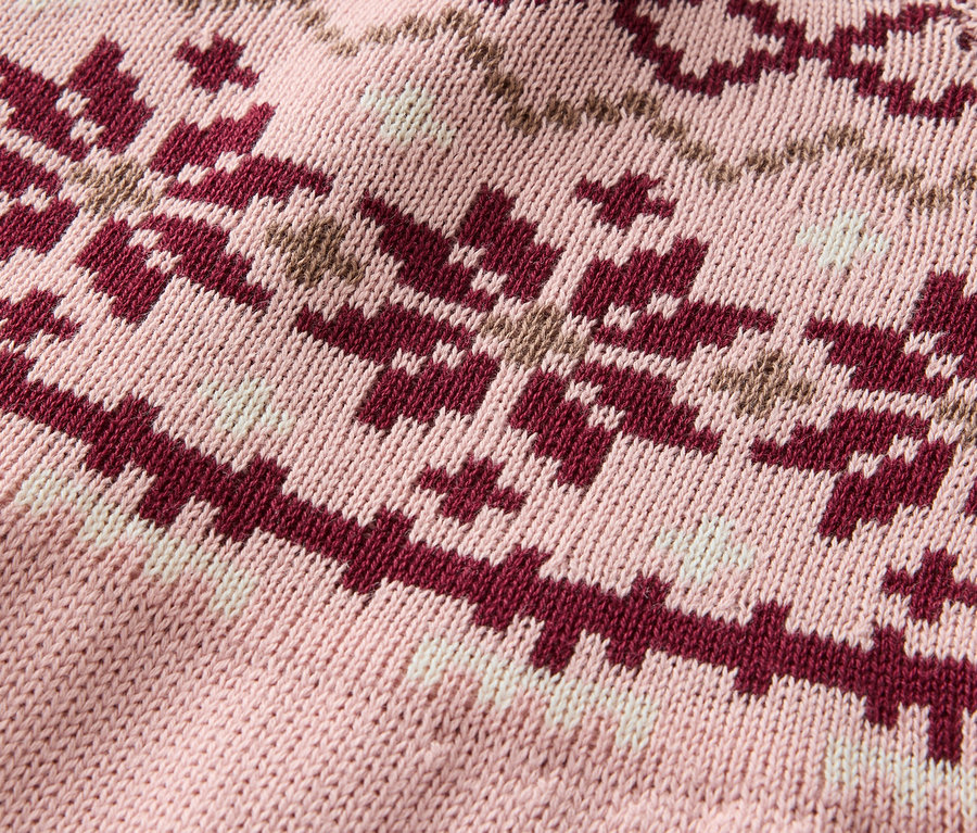 Detail ružového pleteného svetra so vzorom vločiek v bordovej a béžovej farbe.